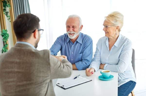 Older couple shaking hands with someone going over paperwork