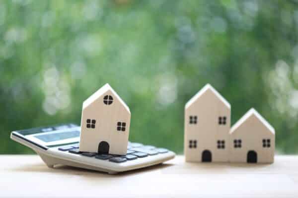 Three wood houses and one is on top of a calculator