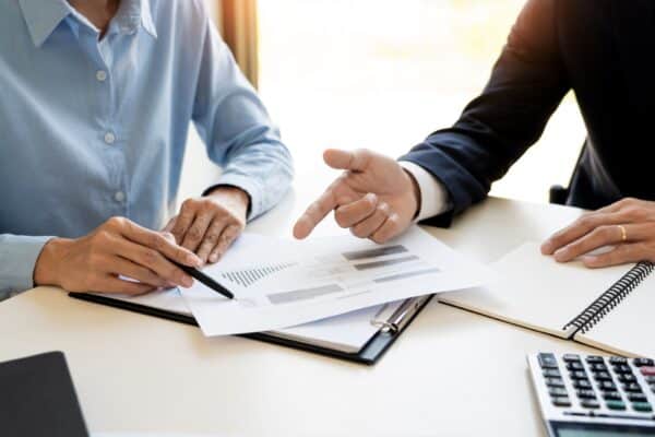 An attorney sitting next to a client at a desk pointing at paperwork.
