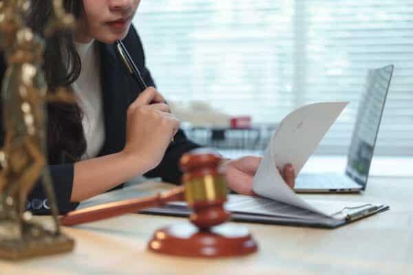 Female lawyer carefully reviewing paperwork next to a gavel and laptop